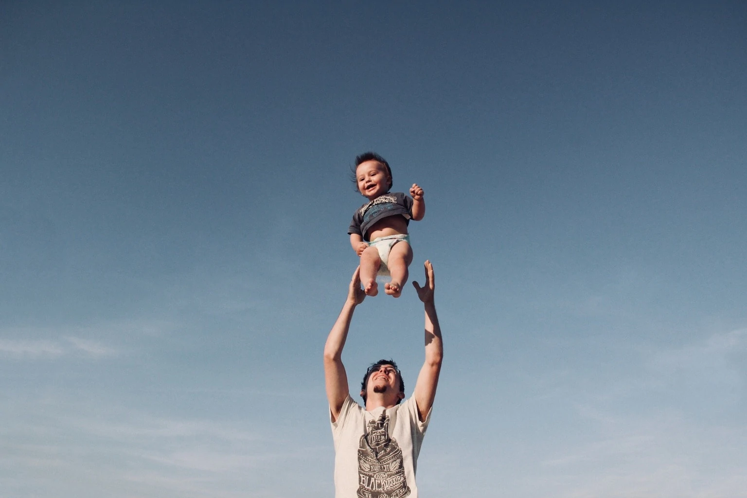 Fotografía de bebé en el aire lanzado por papá