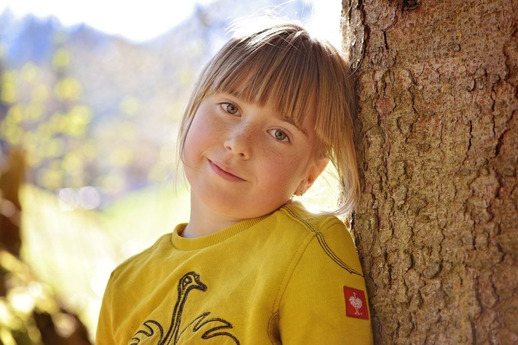 Niña retratada bajo un árbol