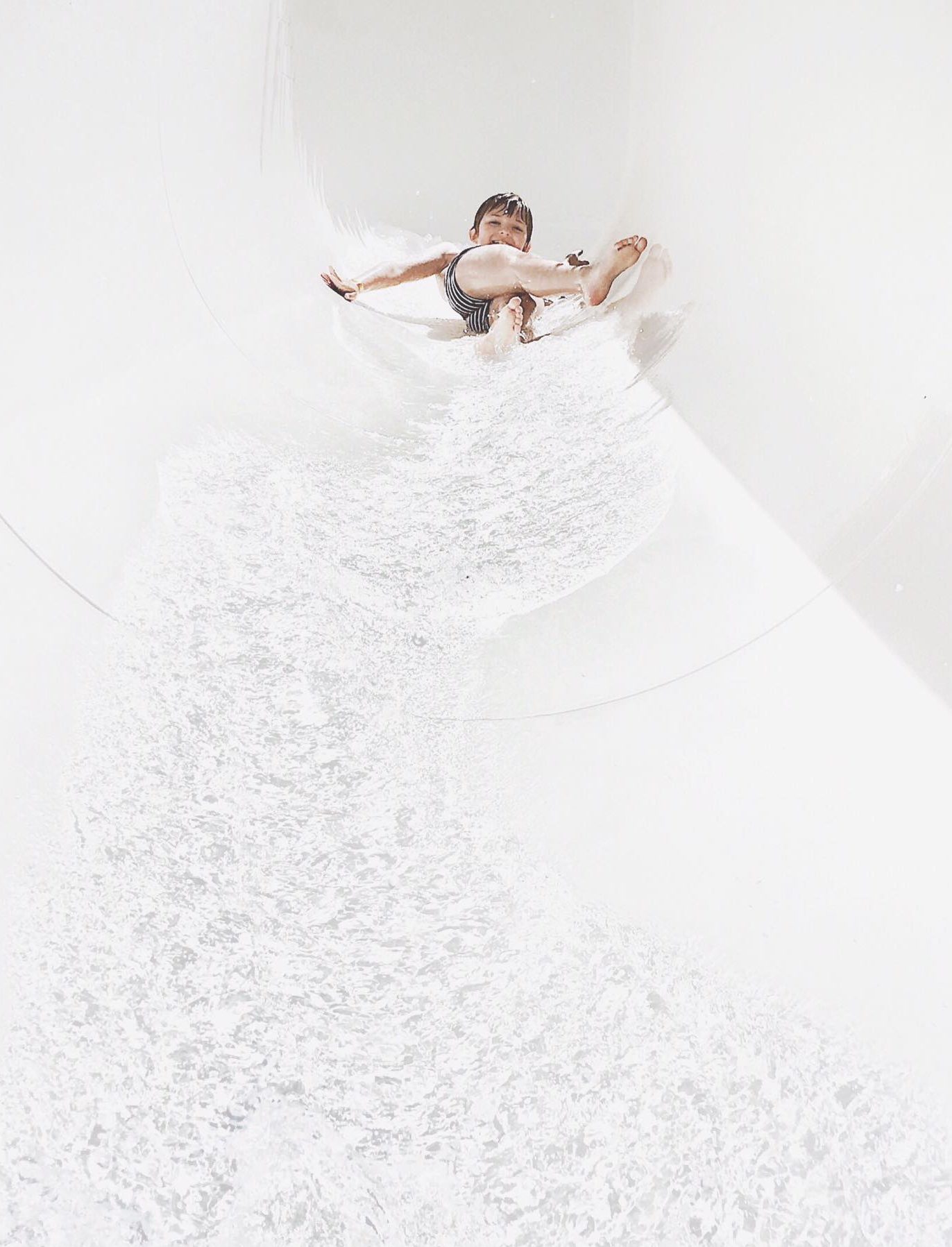 fotografía minimalista niño deslizando en el agua