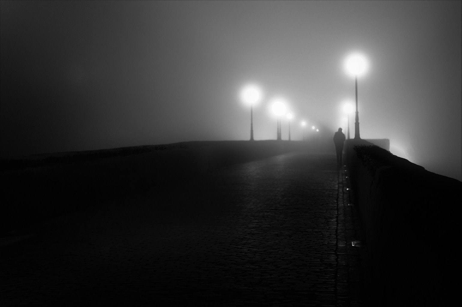 un hombre cruzando un puente entre la niebla