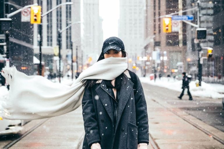 Mujer con bufanda en medio de la calle nevando