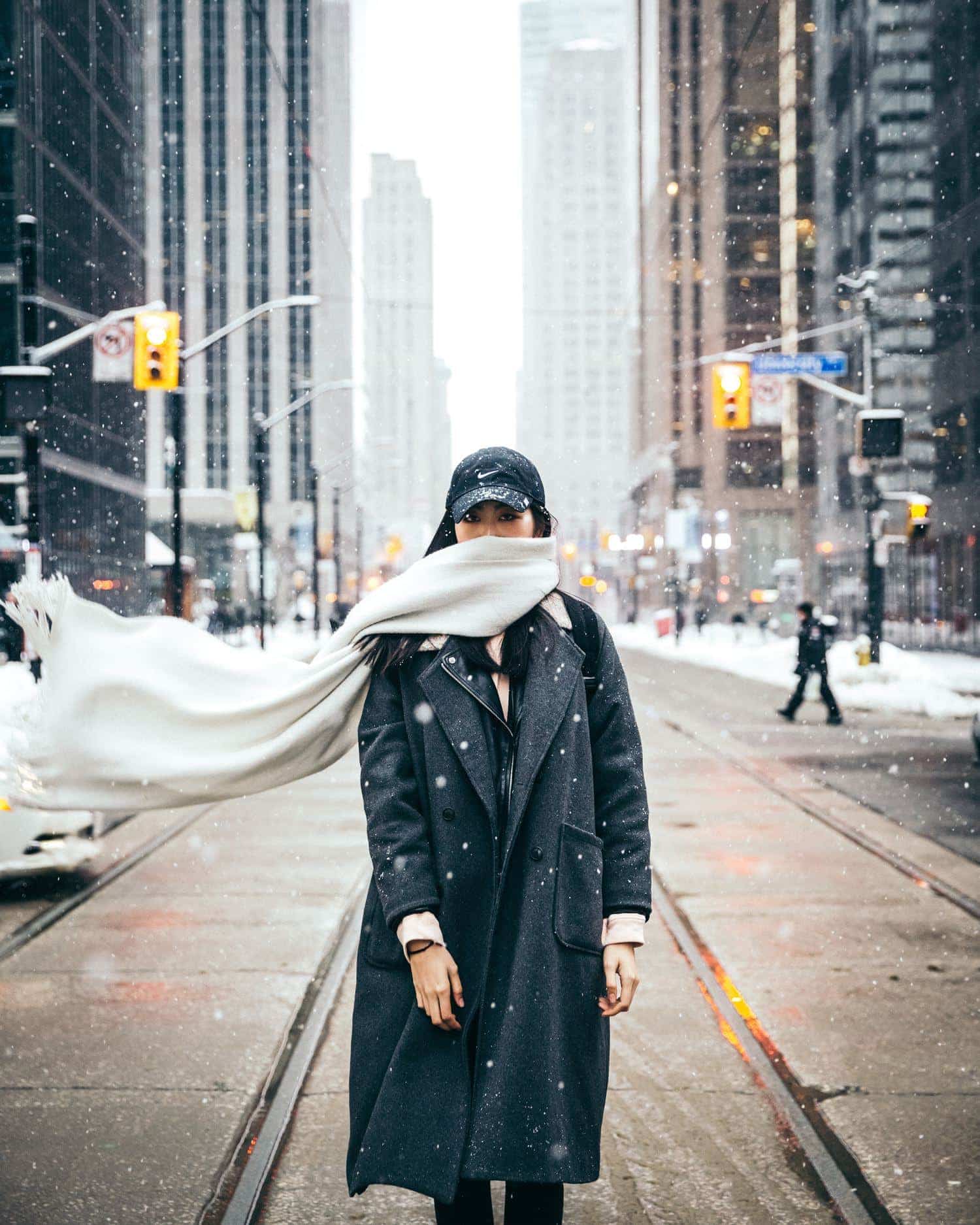 Mujer con bufanda en medio de la calle nevando