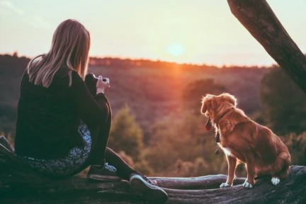 Fotógrafa y perro mirando atardecer