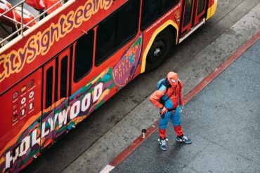 Hombre disfrazado de Spiderman al lado de un bus