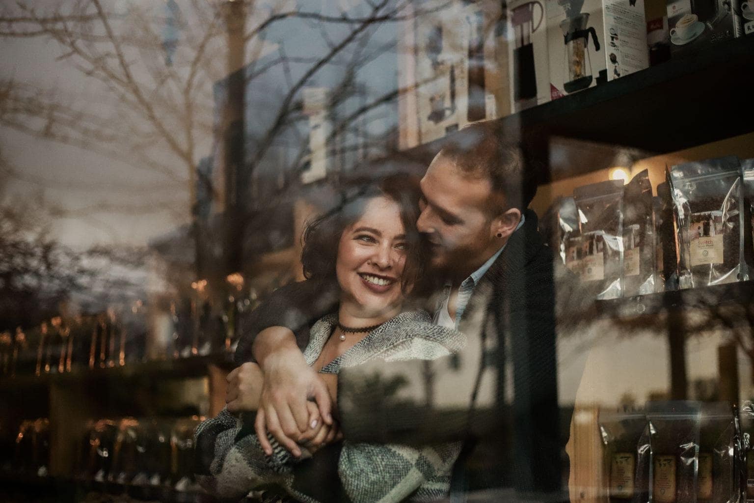 Pareja abrazada detrás de cristal con reflejos