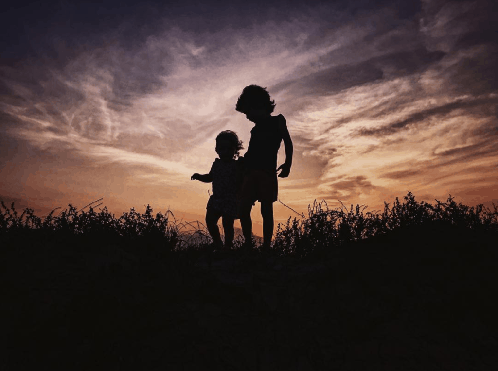 Silueta de hermanos pequeños al atardecer