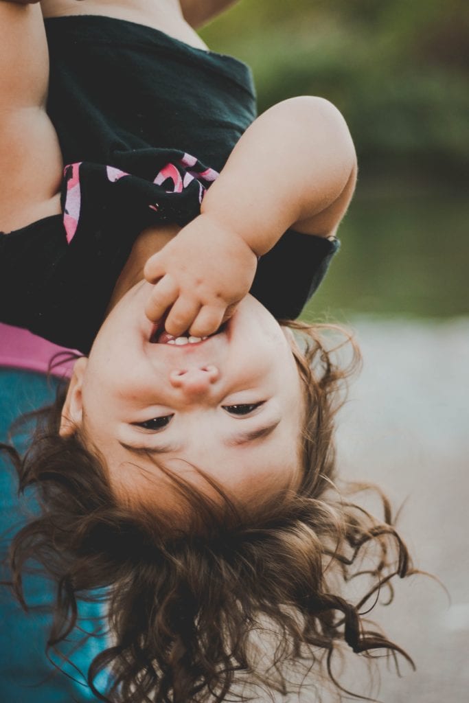 Niña boca abajo riendo