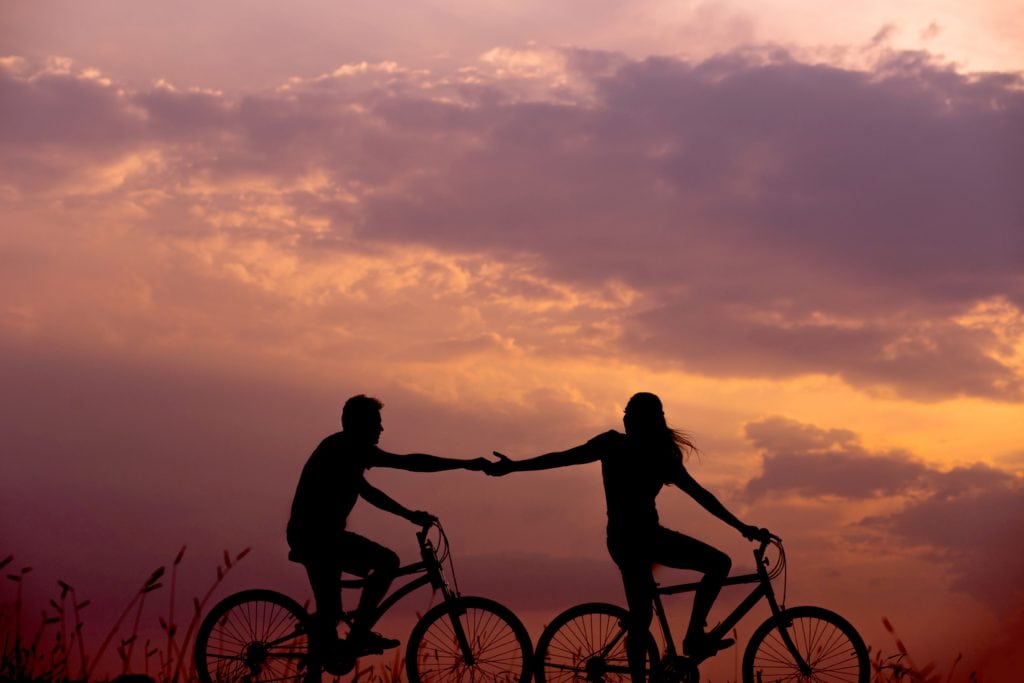 Silueta de pareja montada en bici en un atardecer de verano