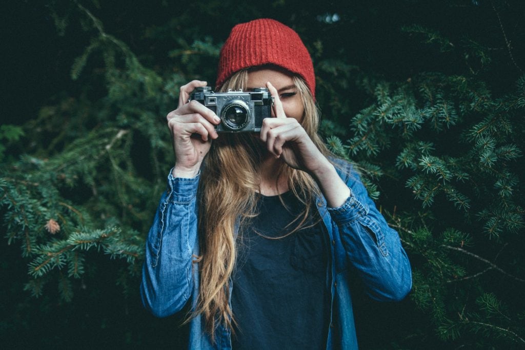 Chica con gorro rojo sosteniendo una cámara