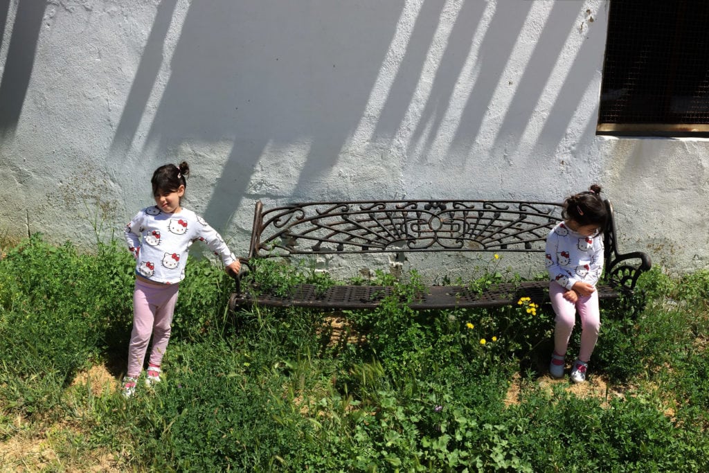 Niña clonada en un banco con fachada de fondo