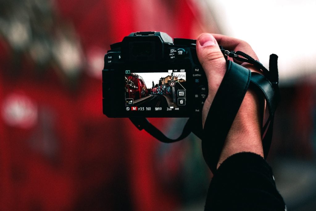 Camara réflex sujeta por una mano con los ajustes de la pantalla visibles