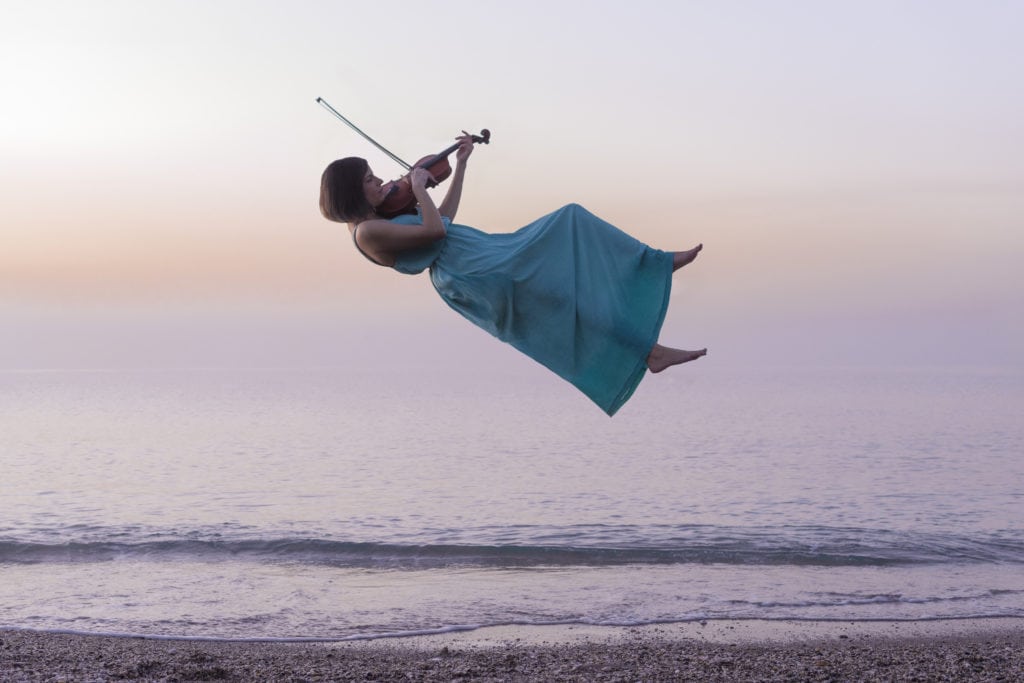 Violinista volando en la orilla de la playa