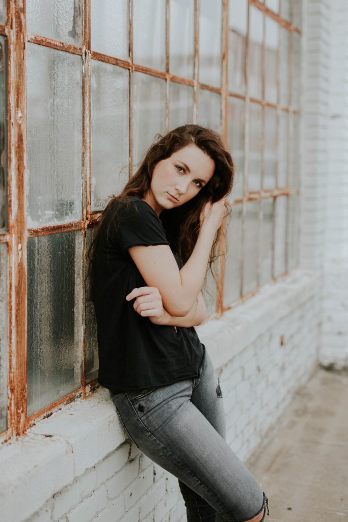 young girl leaning against old window