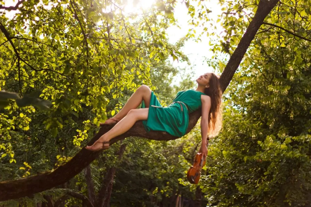 Mujer tumbada en la rama de un árbol