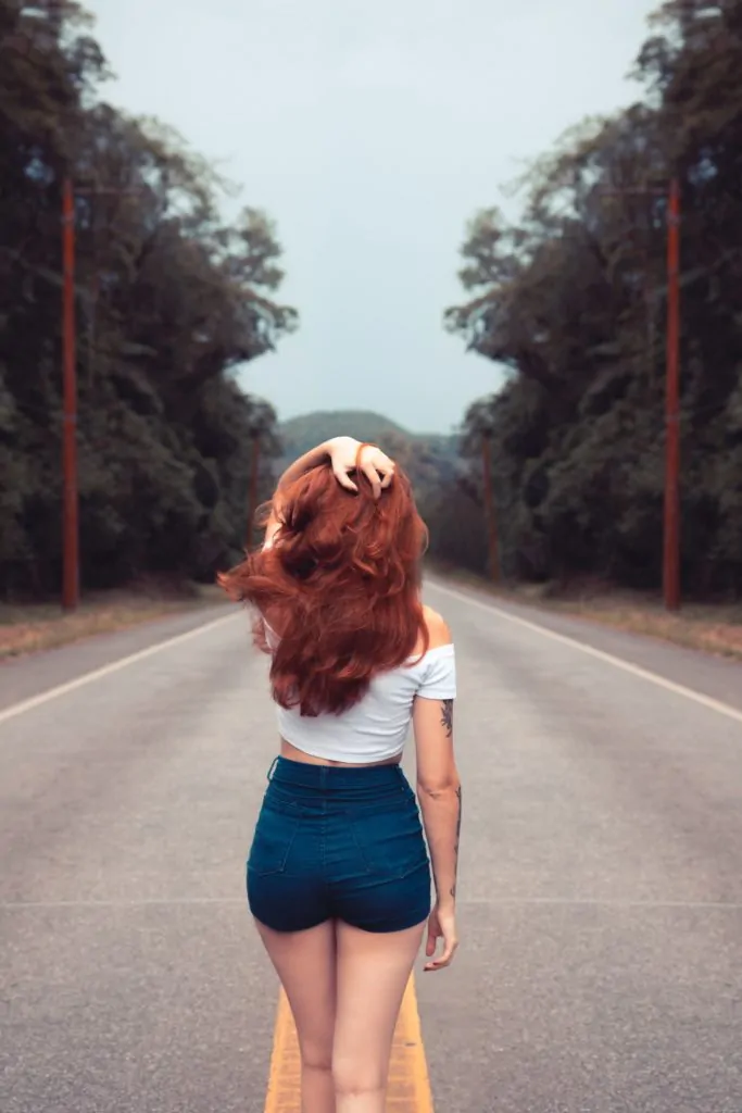 Chica pelirroja en carretera de espaldas