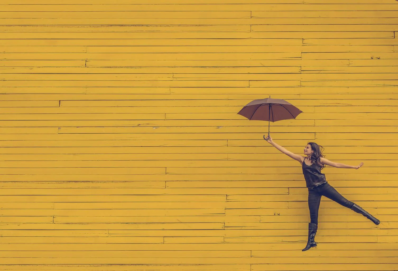 Girl jumping with umbrella in front of yellow facade, color wheel monochrome combination