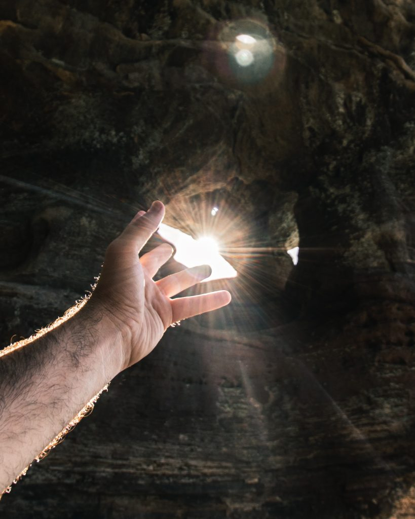 mano dirigida hacia la luz en una cueva