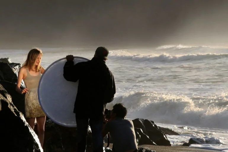 fotógrafos iluminando a modelo con reflector en la playa