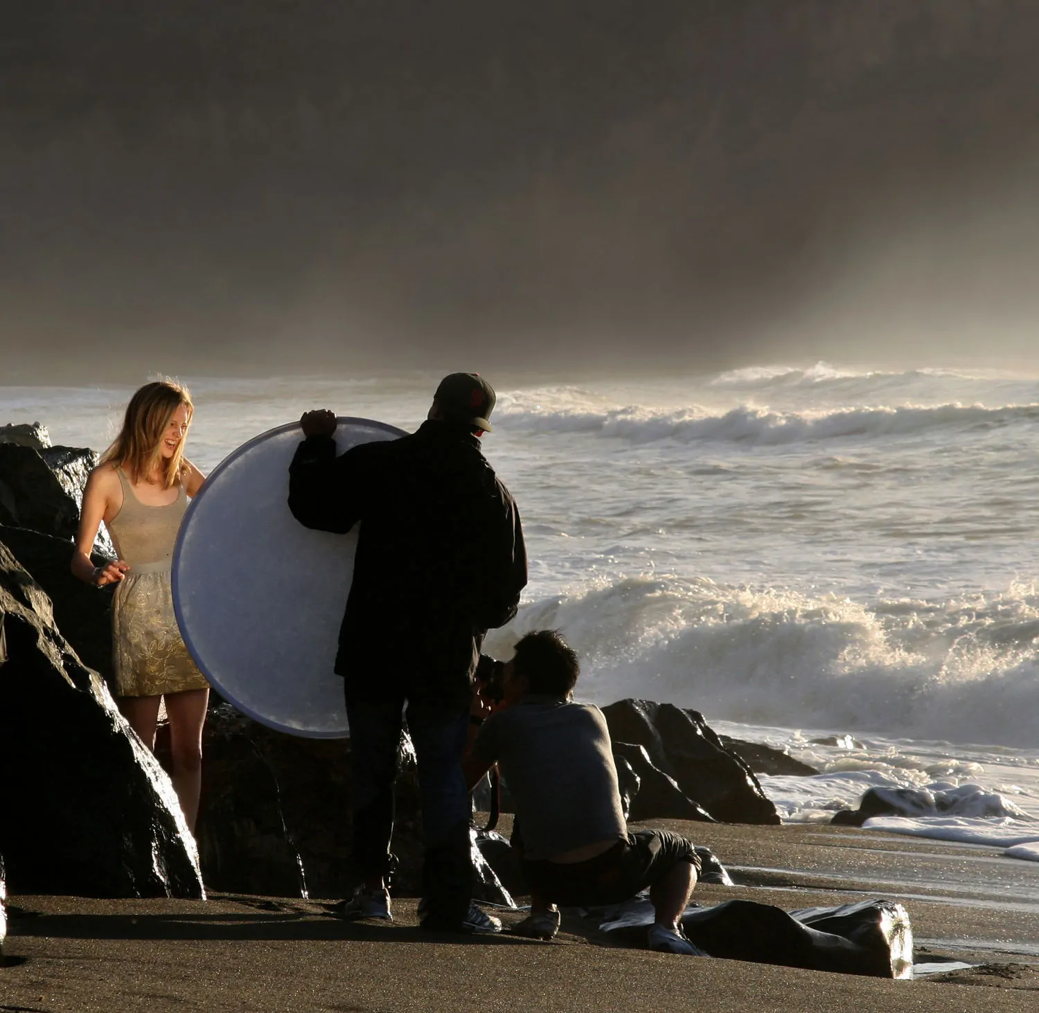 fotógrafos iluminando a modelo con reflector en la playa