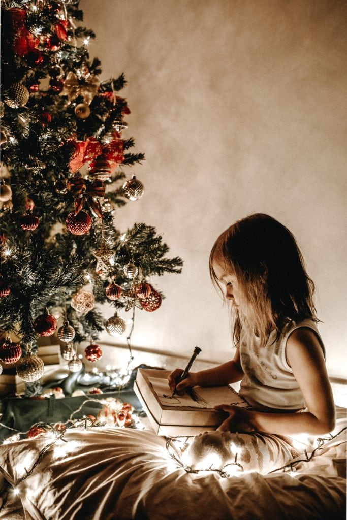 Niña junto a árbol de Navidad