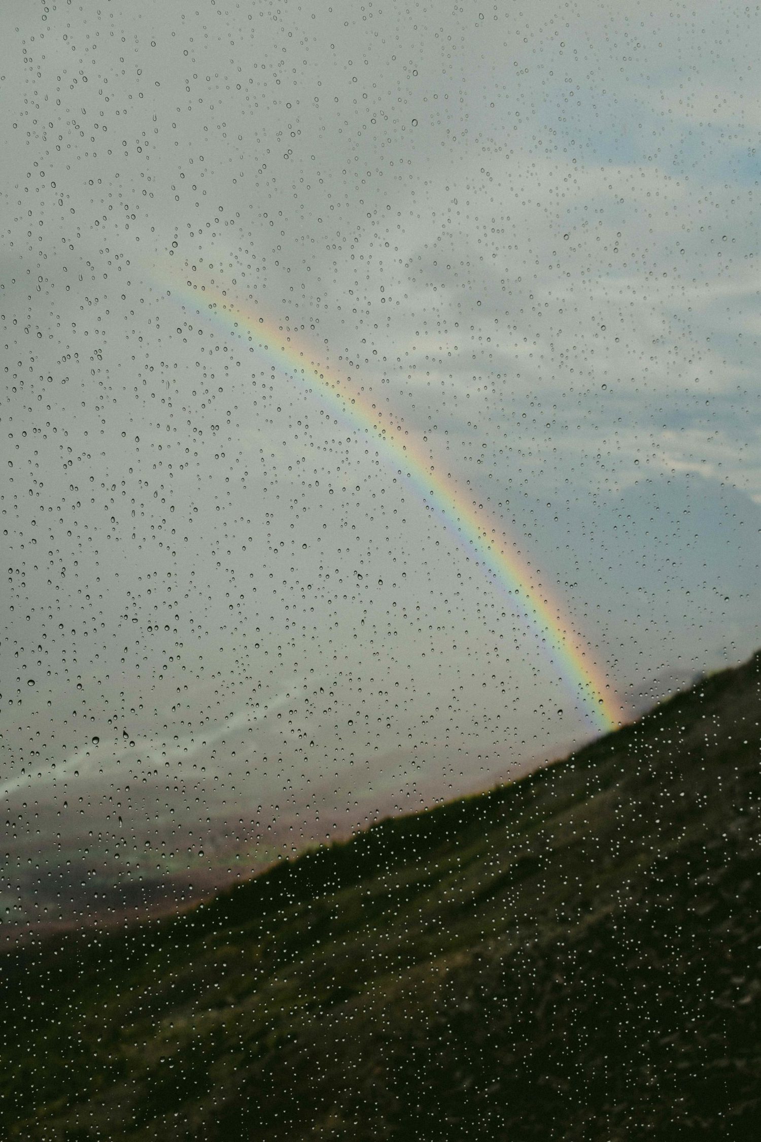 Arcoíris visto desde detrás de cristal con gotas de agua