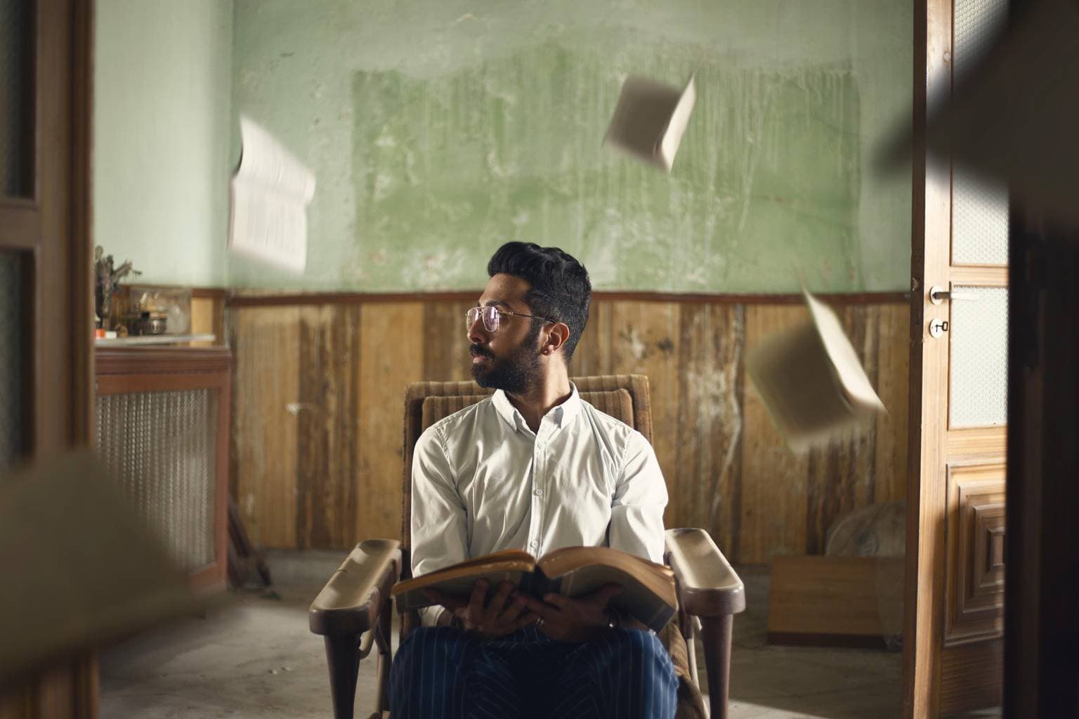 Retrato de hombre en una casa con libros volando