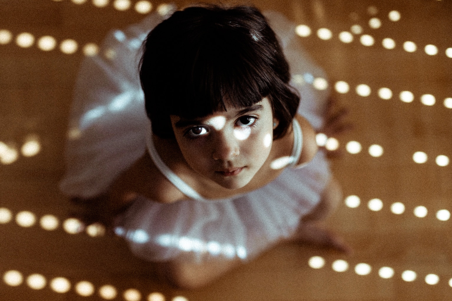 niña vestida de bailarina bañada por la luz de una ventana entre sombras