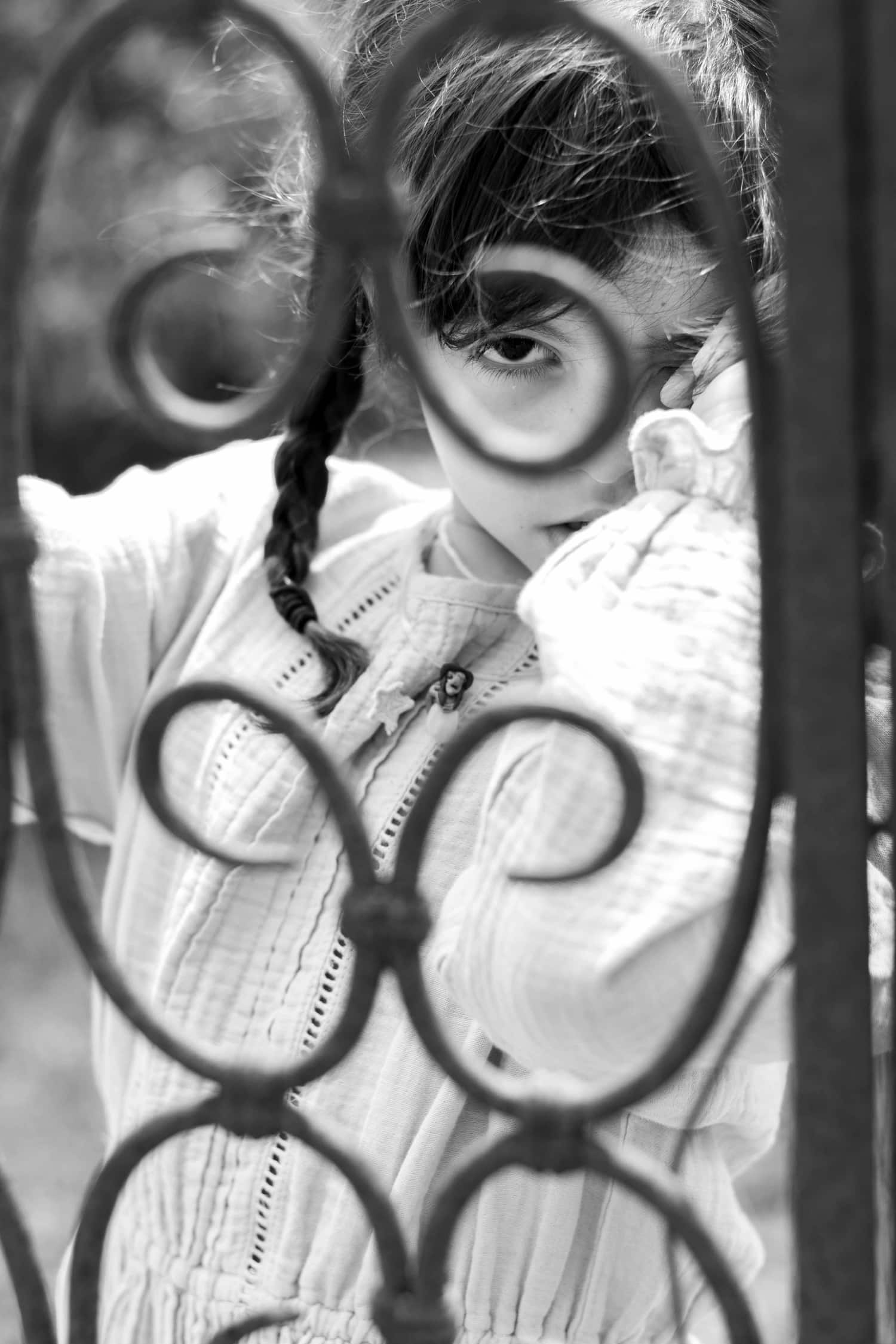 Retrato de niña en blanco y negro detrás de una verja