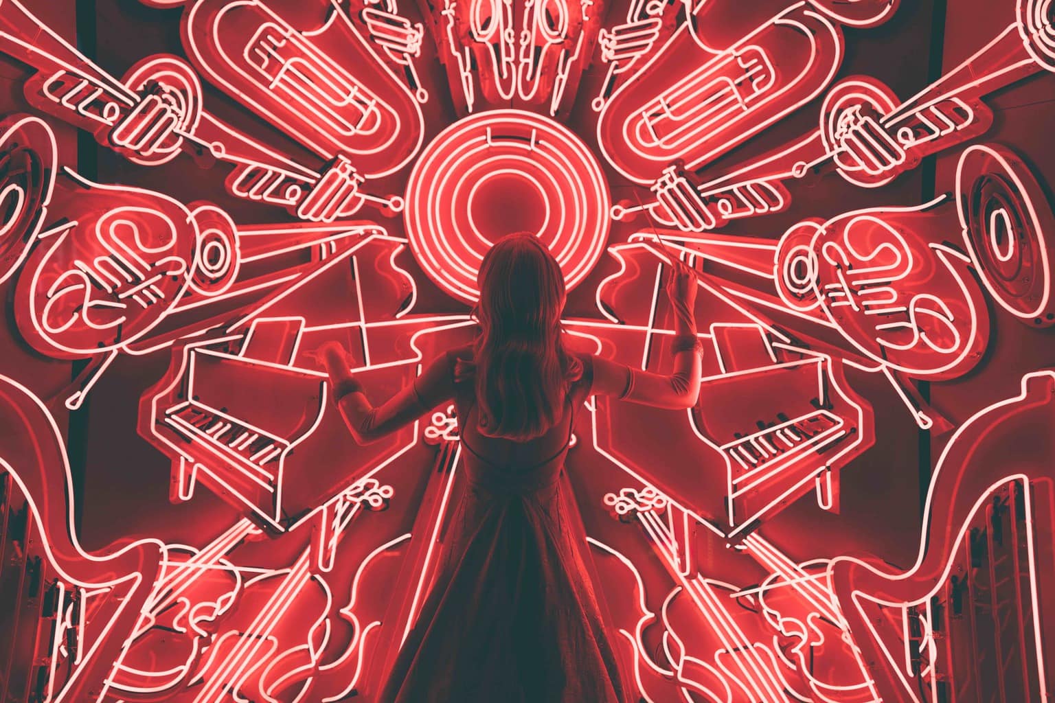 Letrero de neón rojo con chica delante como directora de orquesta