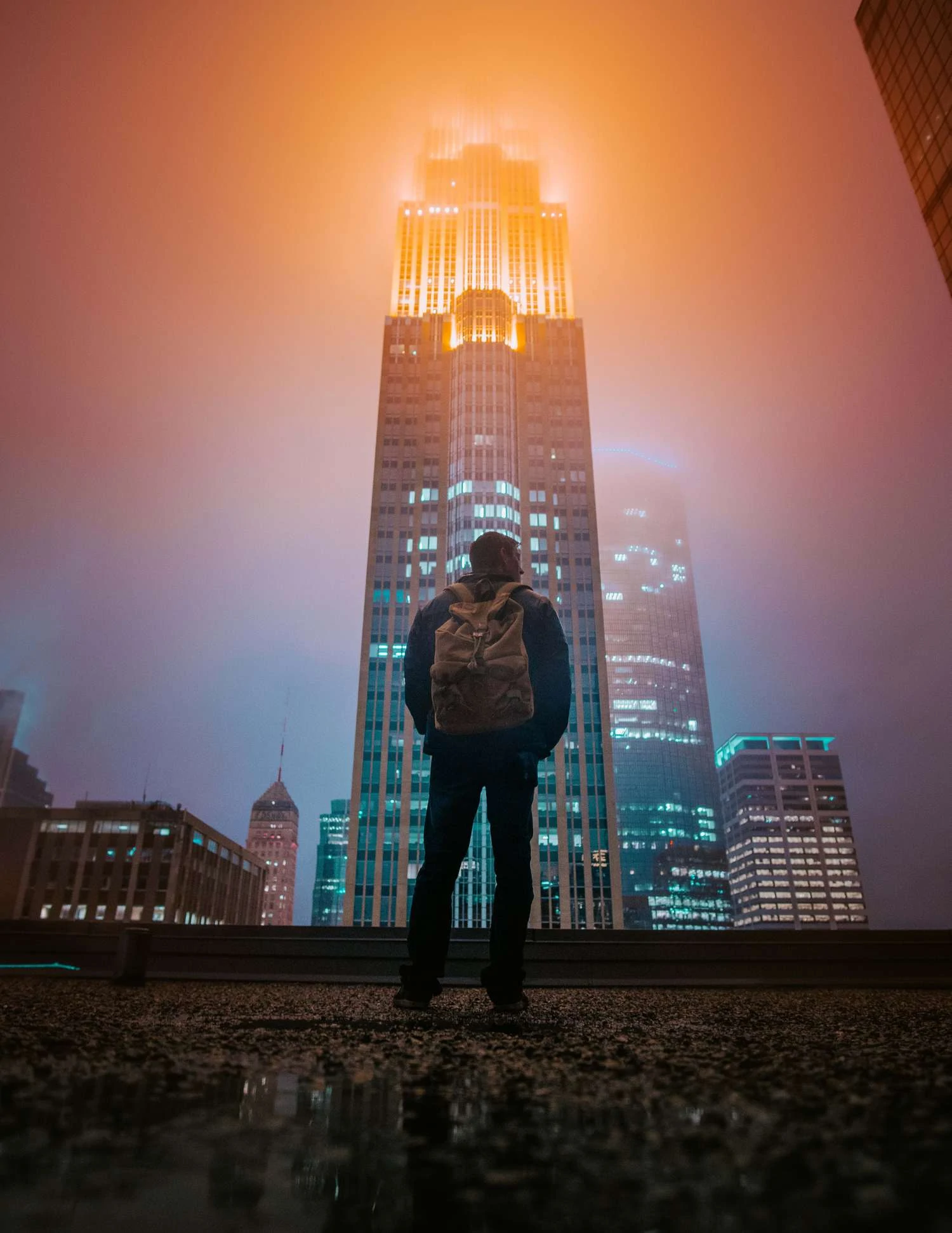 human figure in front of skyscraper with lights on