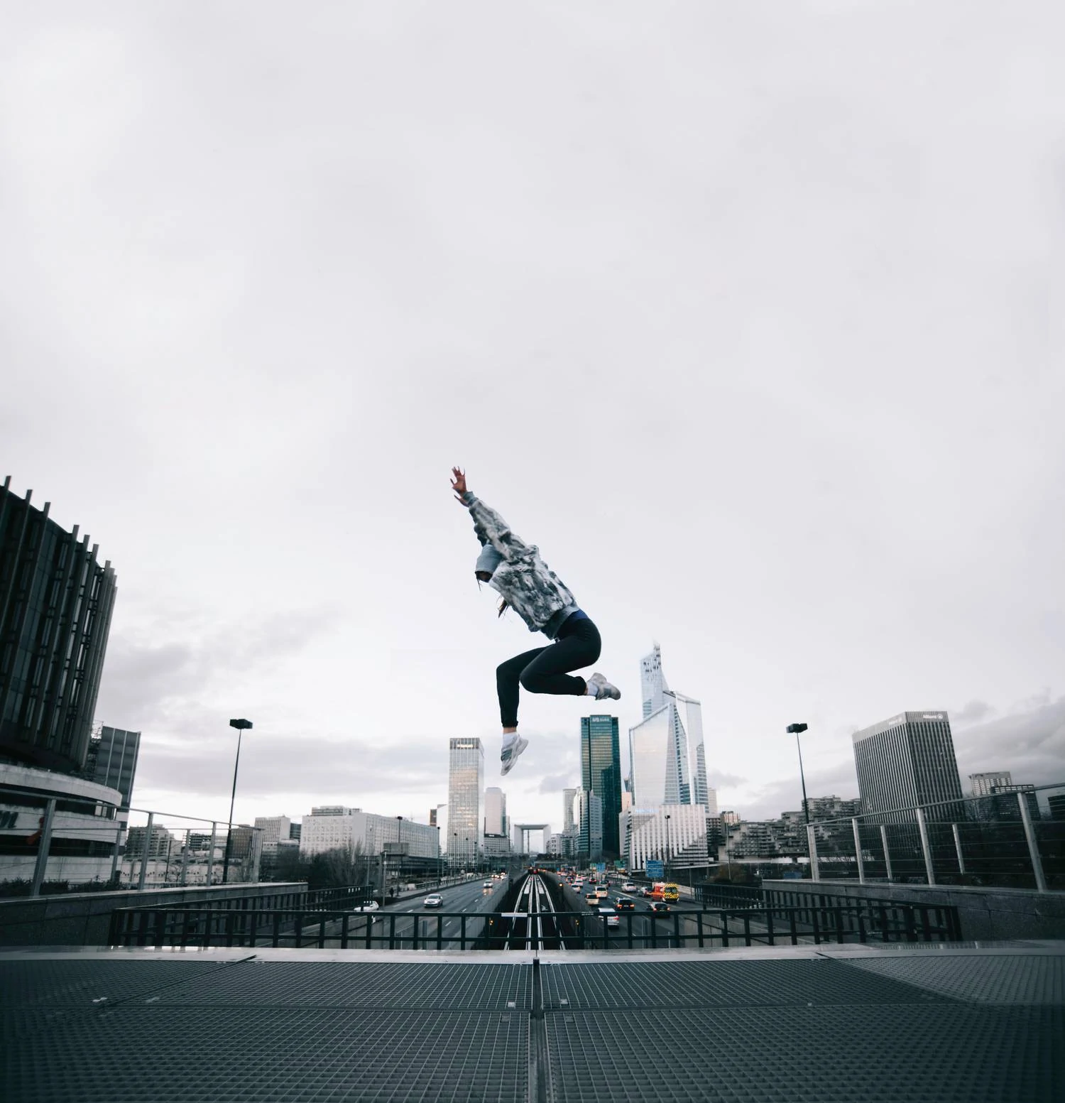 Young man jumping over the road and skyscrapers as an example of urban photography