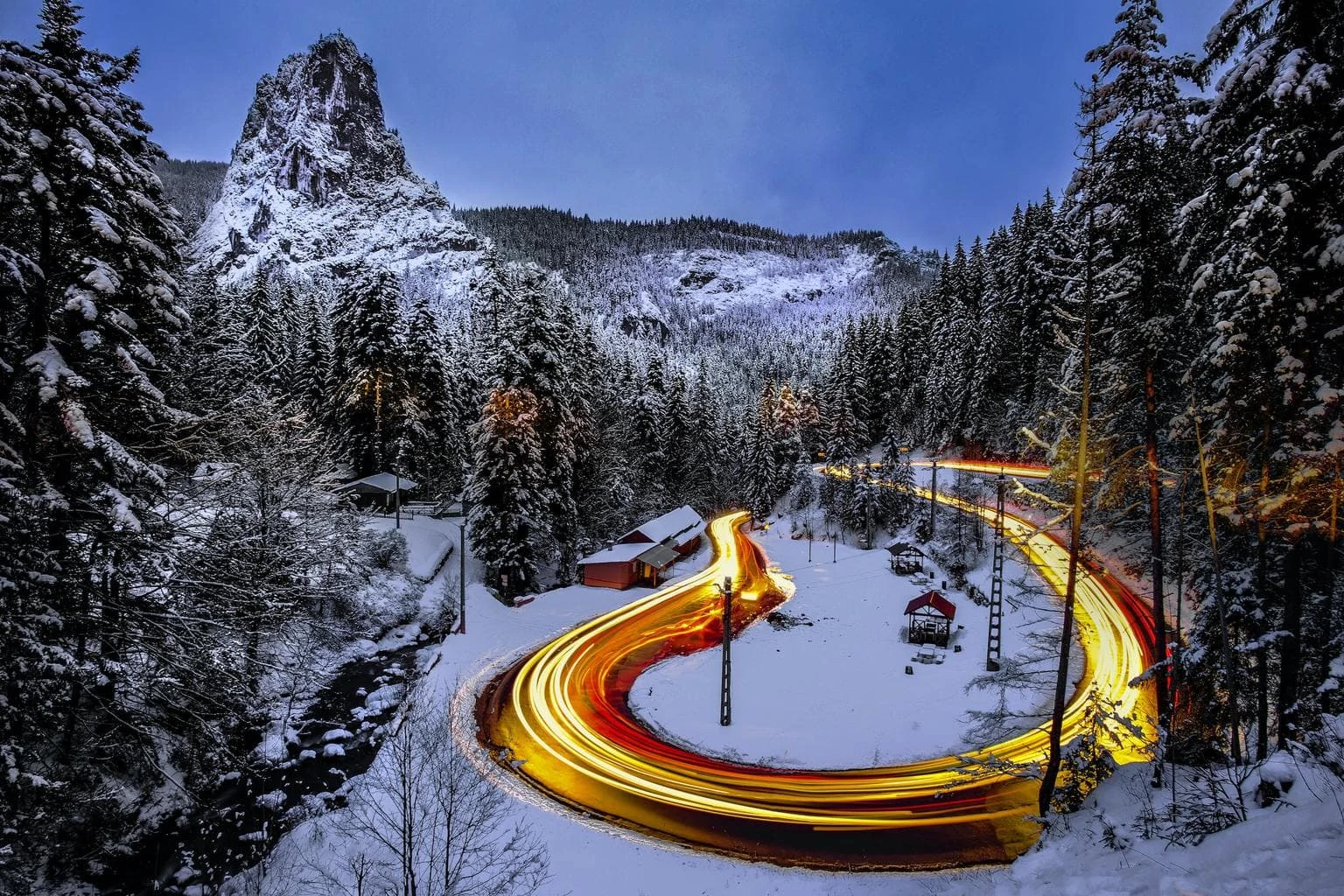 Paisaje de bosque nevado con estelas de luz de coches