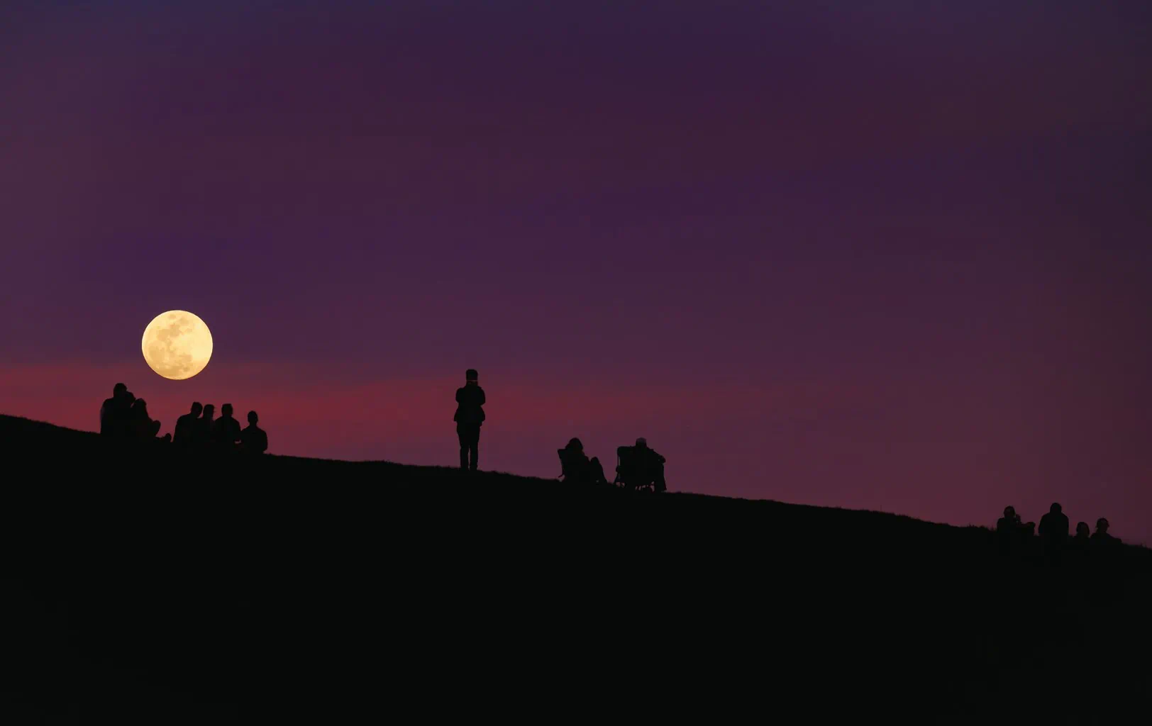 Moon with silhouettes of people