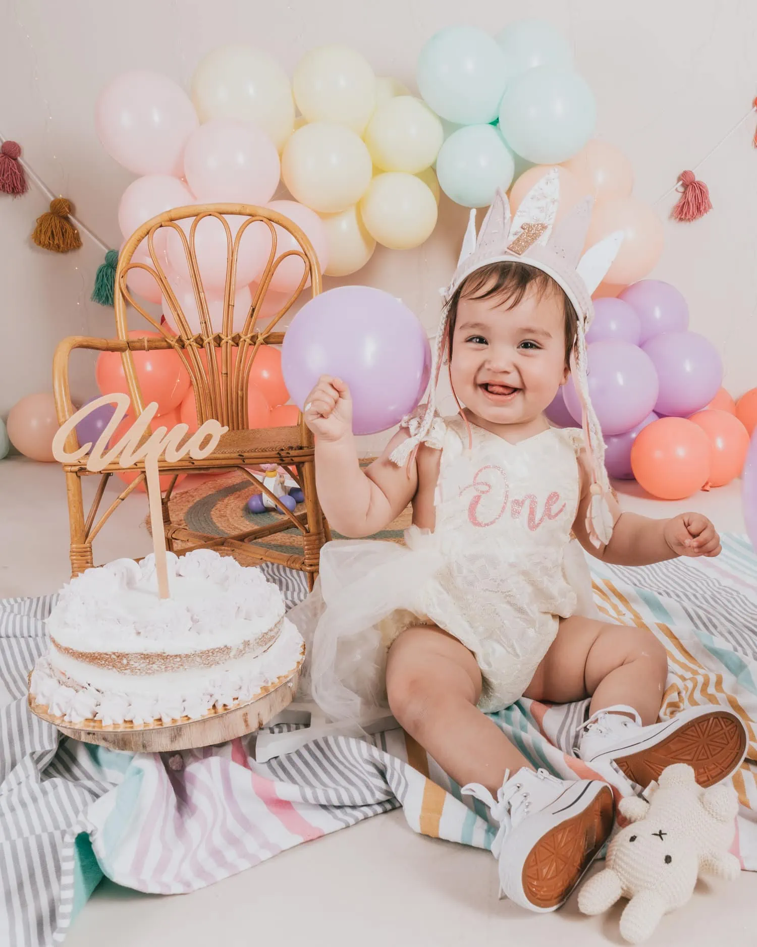 Bebé de 1 año en un estudio fotográfico con un pastel y globos, cumpleaños  de un niño de 1 año, el bebé come pastel