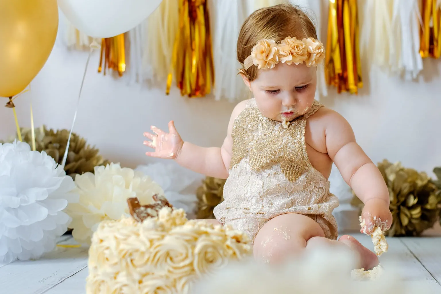 Bebé de 1 año en un estudio fotográfico con un pastel y globos