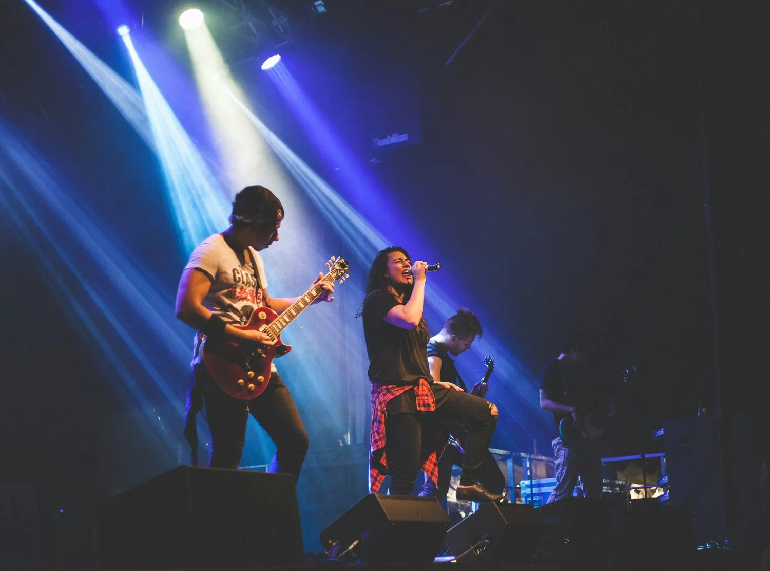 Fotografía en escenario oscuro con cantante y músicos