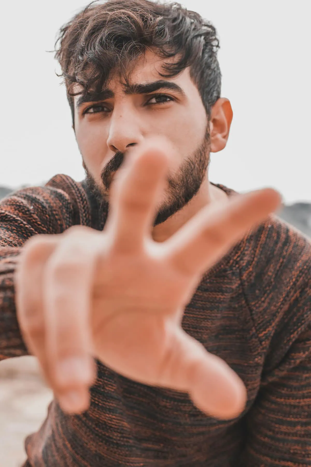 Retrato creativo de un hombre con barba en primer plano y mano desenfocada acercándose