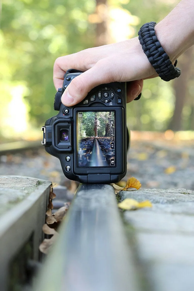 Cámara réflex digital sostenida a ras del suelo, composición fotográfica con ángulo bajo
