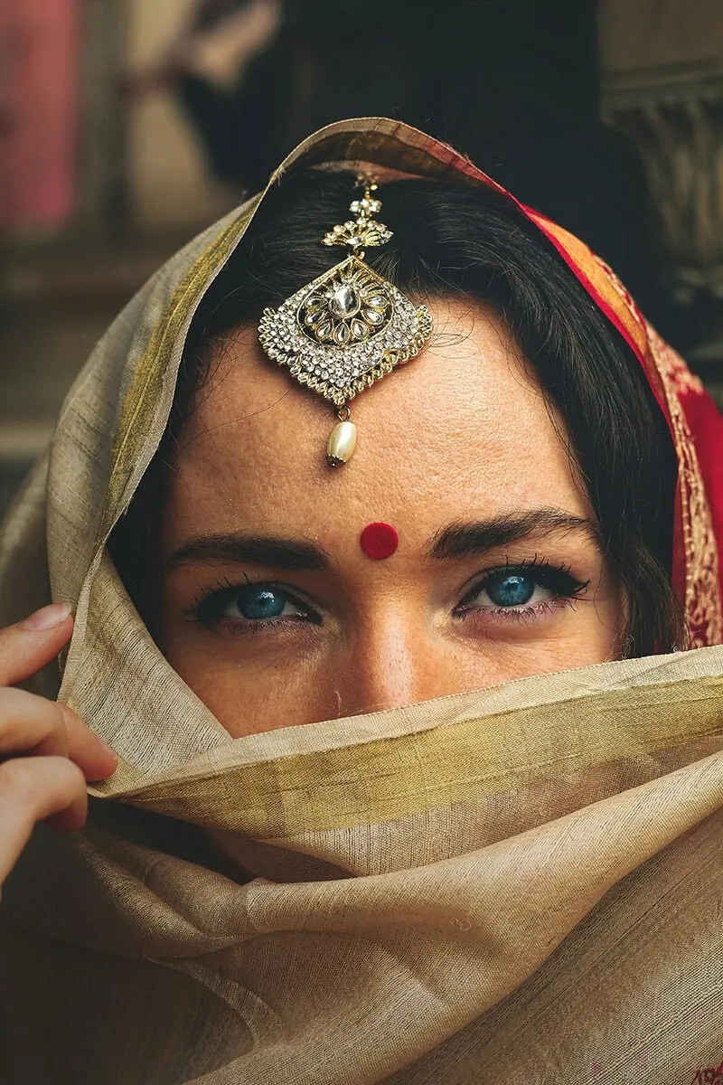 Primer plano de una mujer con joyería tradicional india y velo, tomada con un lente ideal para retrato