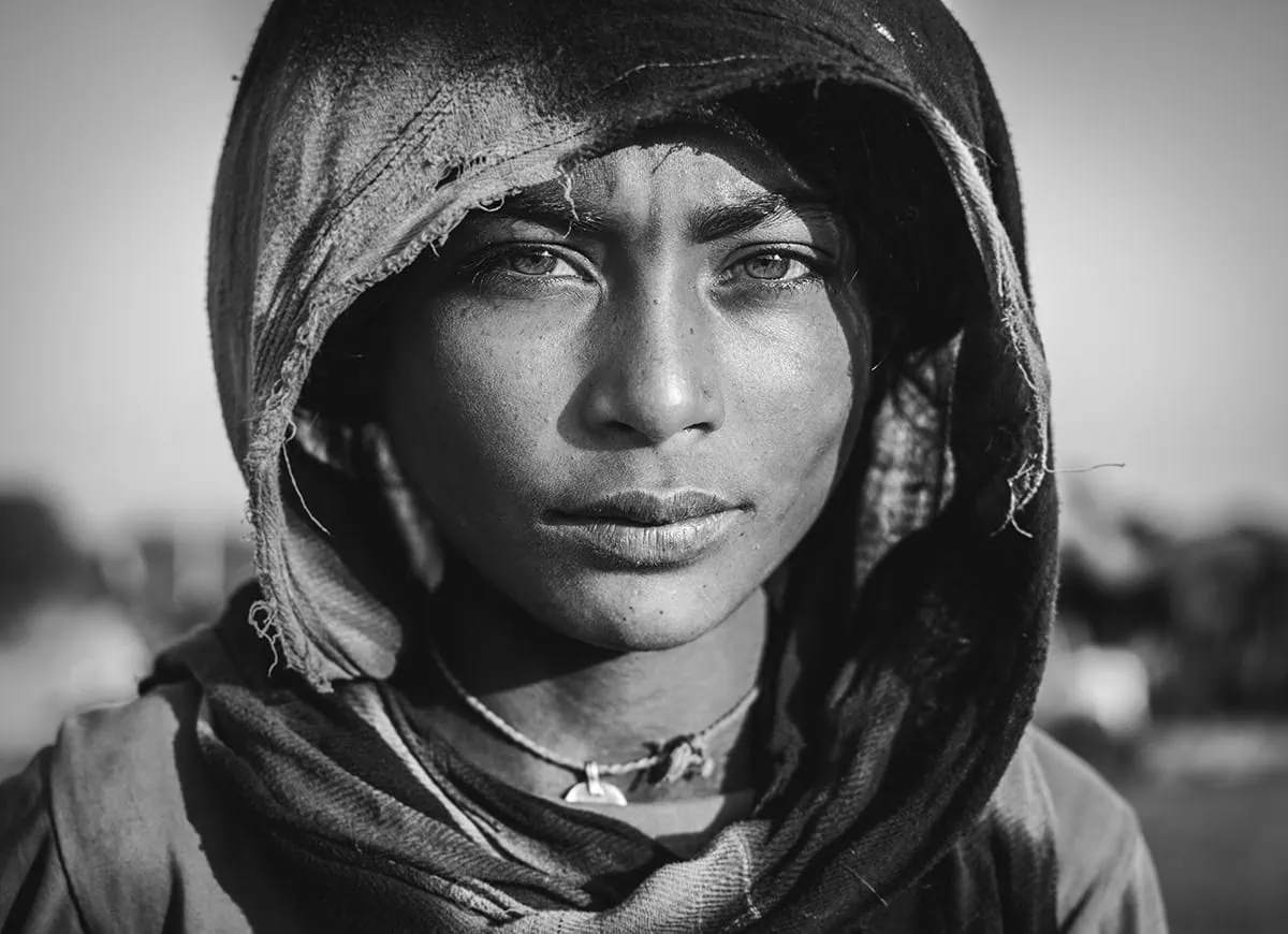 Retrato en blanco y negro de una joven con capucha, realizado con un teleobjetivo ideal para capturar expresividad en retratos.