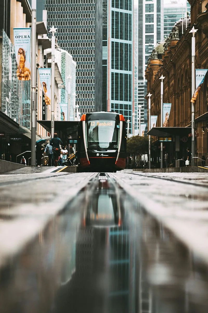 Tranvía urbano en una calle moderna con reflejo en el suelo mojado, ejemplo de tendencias en retoque fotográfico 2025