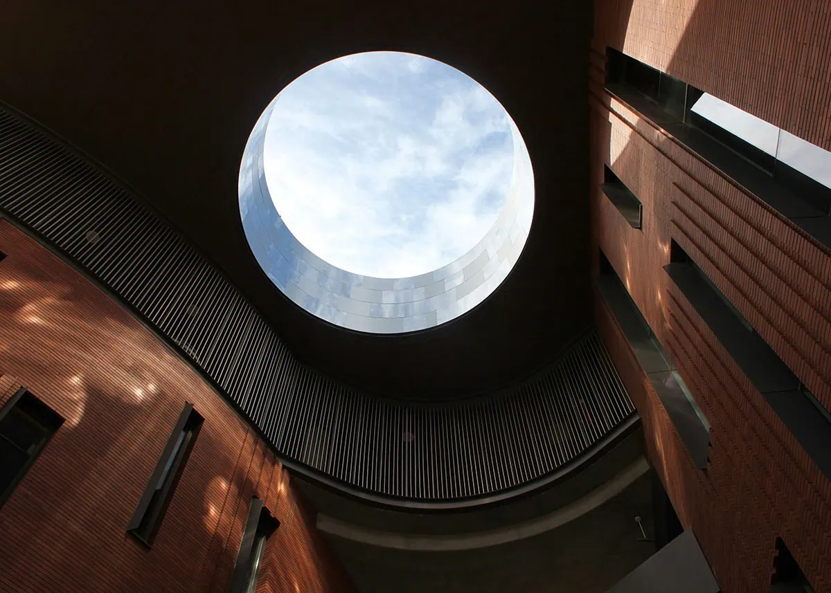 fotografía arquitectónica tomada desde el interior de un edificio, mostrando un óculo circular que enmarca el cielo