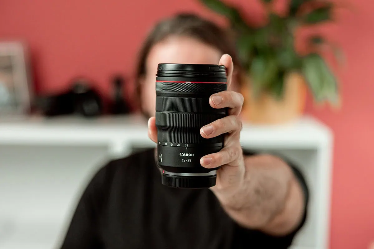 elección de objetivos fotográficos, mano sosteniendo un lente fotográfico